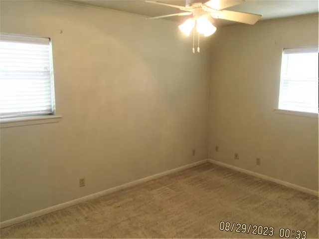 an empty room with a window and a fan