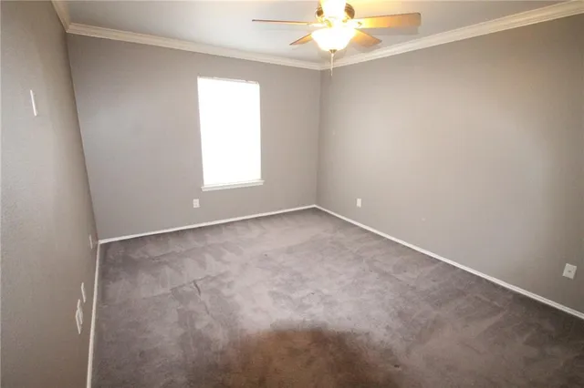 an empty room with a chandelier fan and windows