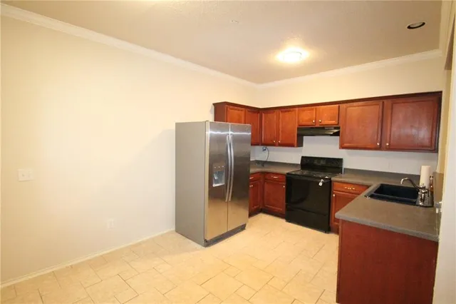 a kitchen with granite countertop a refrigerator and a stove top oven
