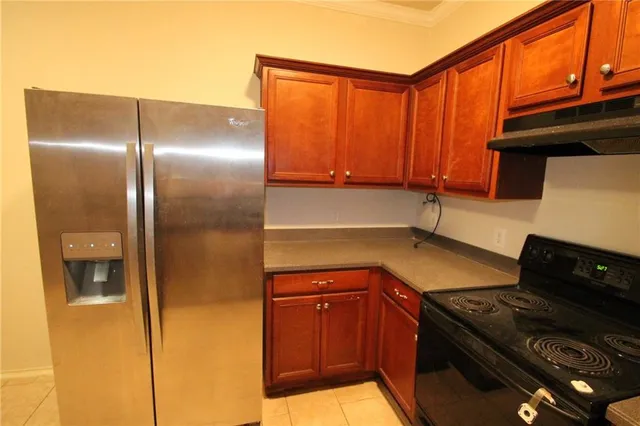 a kitchen with granite countertop a refrigerator and a stove top oven