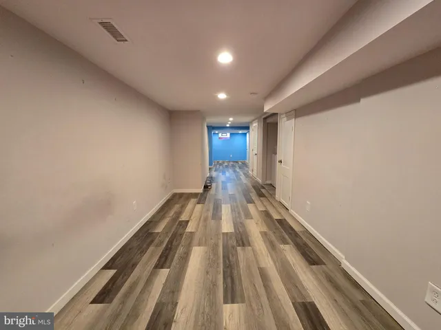an empty room with wooden floor a ceiling fan and windows