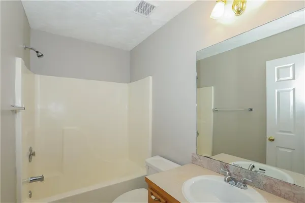 a bathroom with a granite countertop sink a mirror and a bathtub
