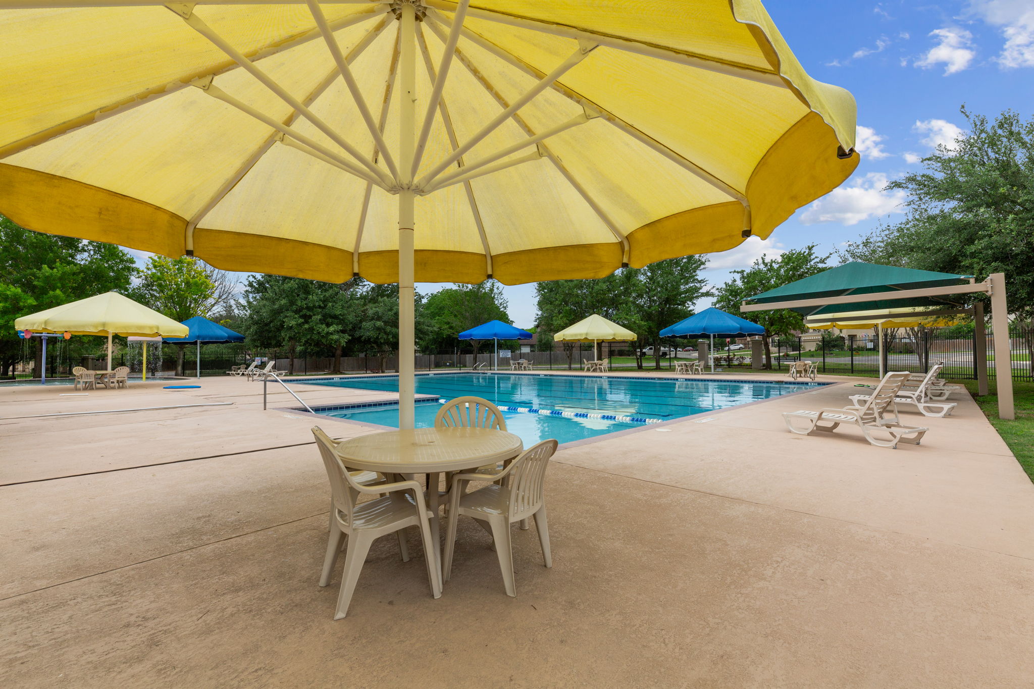 310 Myrtle Street Kyle, TX 78640 - Photo 33 of 39 Resort-style pool area featuring ample seating, sun loungers, multiple shaded cabanas, and a spacious concrete deck
