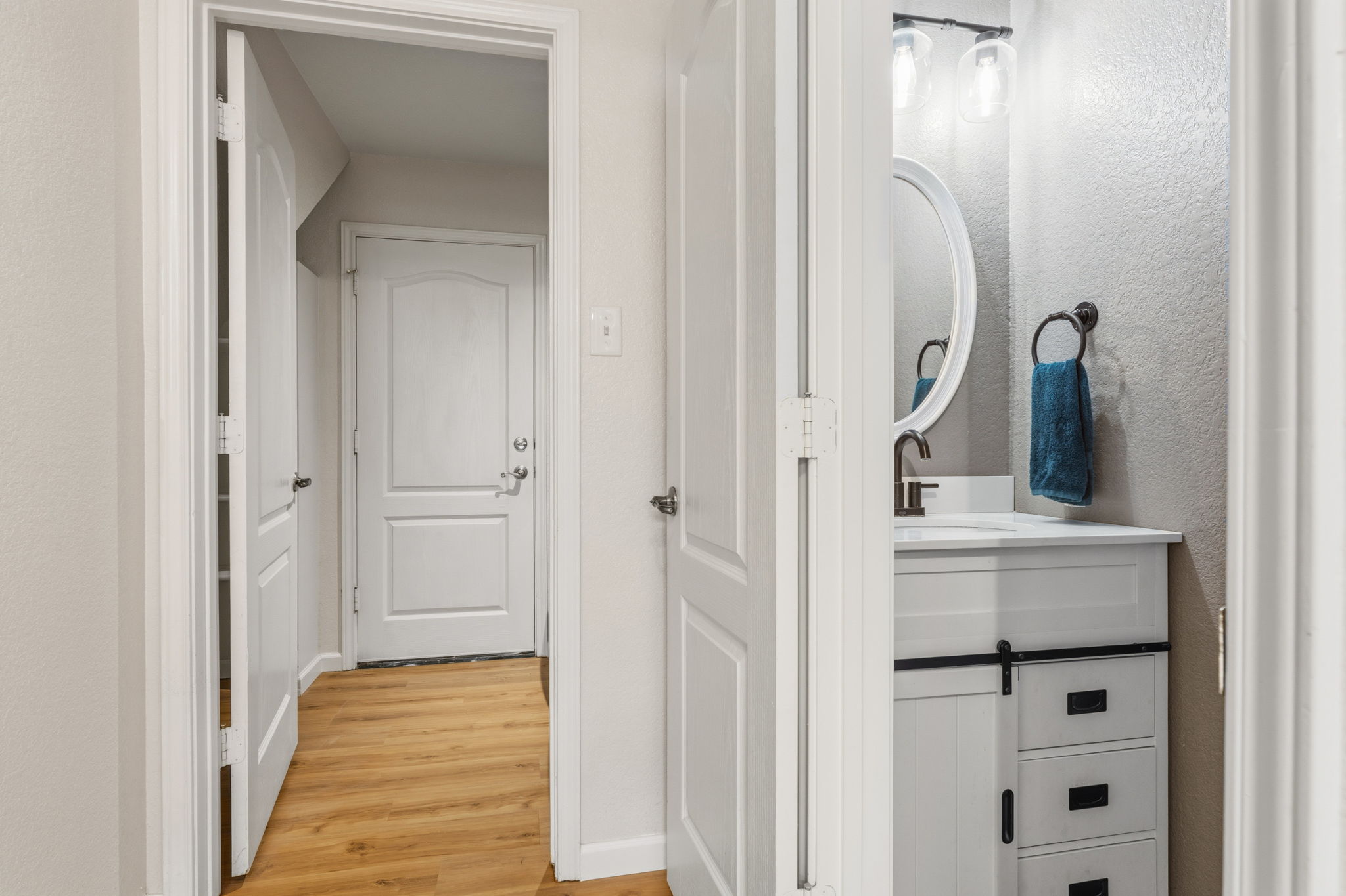 310 Myrtle Street Kyle, TX 78640 - Photo 10 of 39 Powder room downstairs featuring a white vanity with a sliding barn door accent, dark bronze hardware, a white oval sink with dark bronze faucet, and an oval mirror