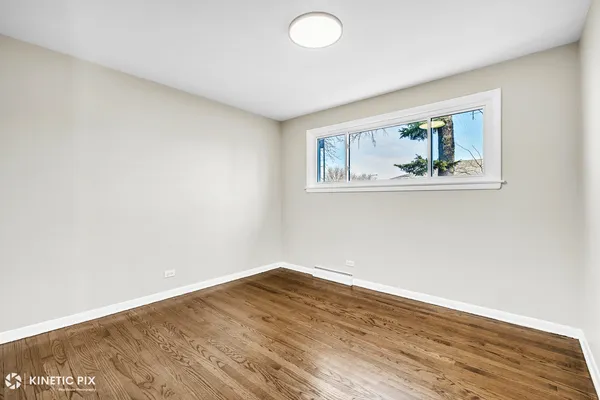 an empty room with wooden floor and window