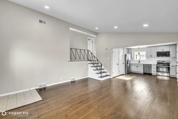 a view of an empty room with wooden floor and stairs
