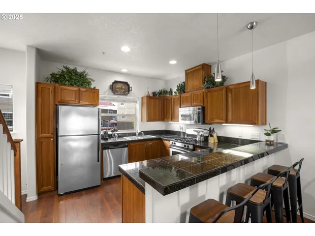 a kitchen with stainless steel appliances granite countertop a stove a sink and a refrigerator