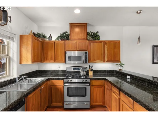 a kitchen with granite countertop a stove top oven a sink dishwasher and a microwave