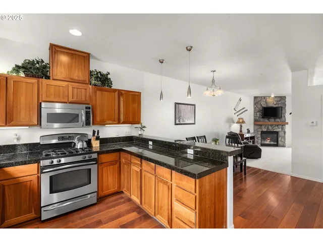 a kitchen with stainless steel appliances granite countertop a sink a stove and a wooden floor