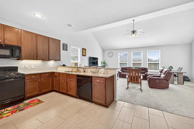 a kitchen with stainless steel appliances granite countertop a stove top oven a sink dishwasher and a microwave oven on the granite countertops