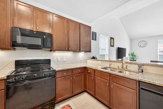 a kitchen with granite countertop stainless steel appliances a sink stove top oven and cabinets