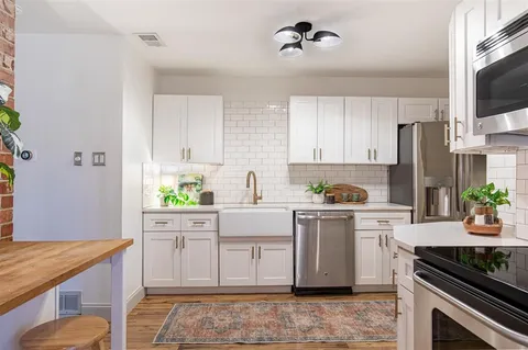a kitchen with stainless steel appliances a stove a sink a refrigerator cabinets and a window