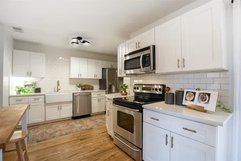a kitchen with cabinets stainless steel appliances a sink and wooden floor