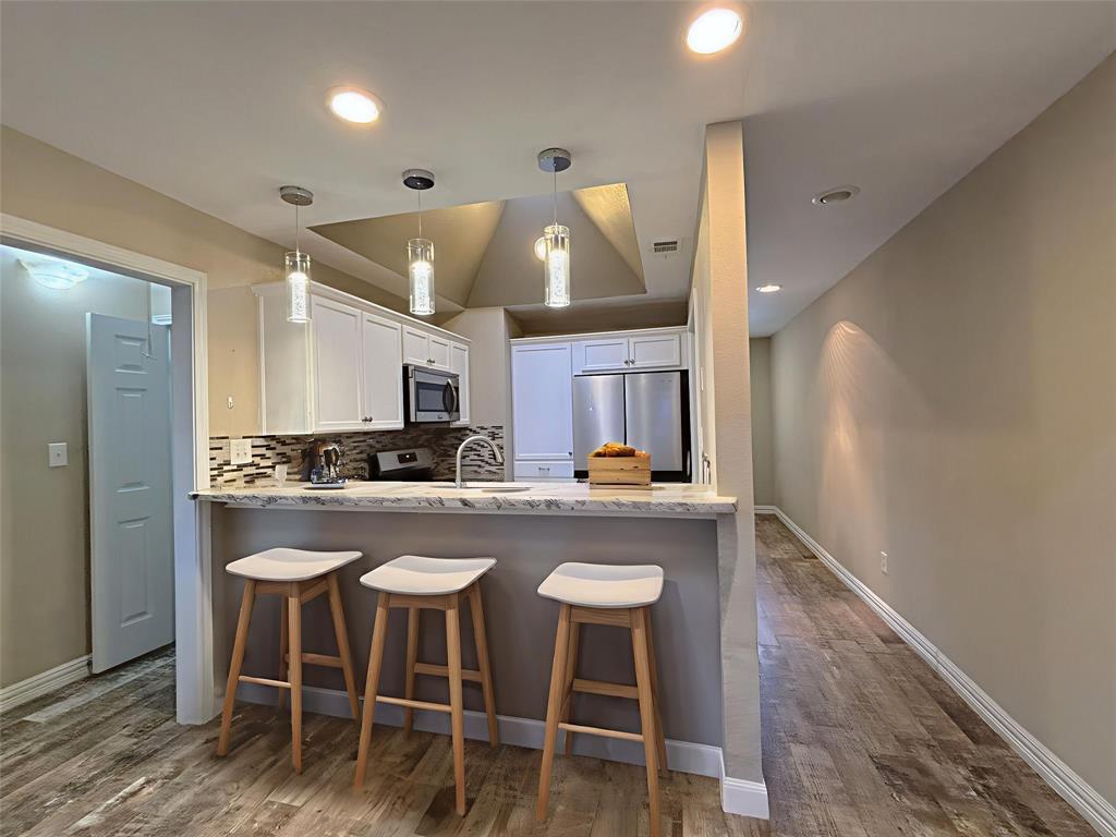9461 Timberleaf Drive Dallas, TX 75243 - Photo 13 of 32 a kitchen with stainless steel appliances a dining table chairs and wooden floor