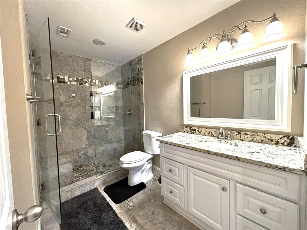 9461 Timberleaf Drive Dallas, TX 75243 - Photo 20 of 32 a bathroom with a sink toilet a mirror and shower