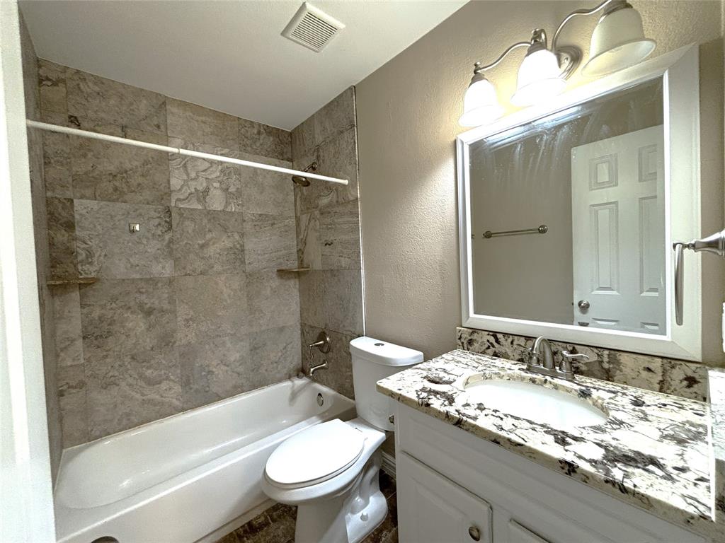 9461 Timberleaf Drive Dallas, TX 75243 - Photo 24 of 32 a bathroom with a granite countertop sink toilet mirror and bathtub
