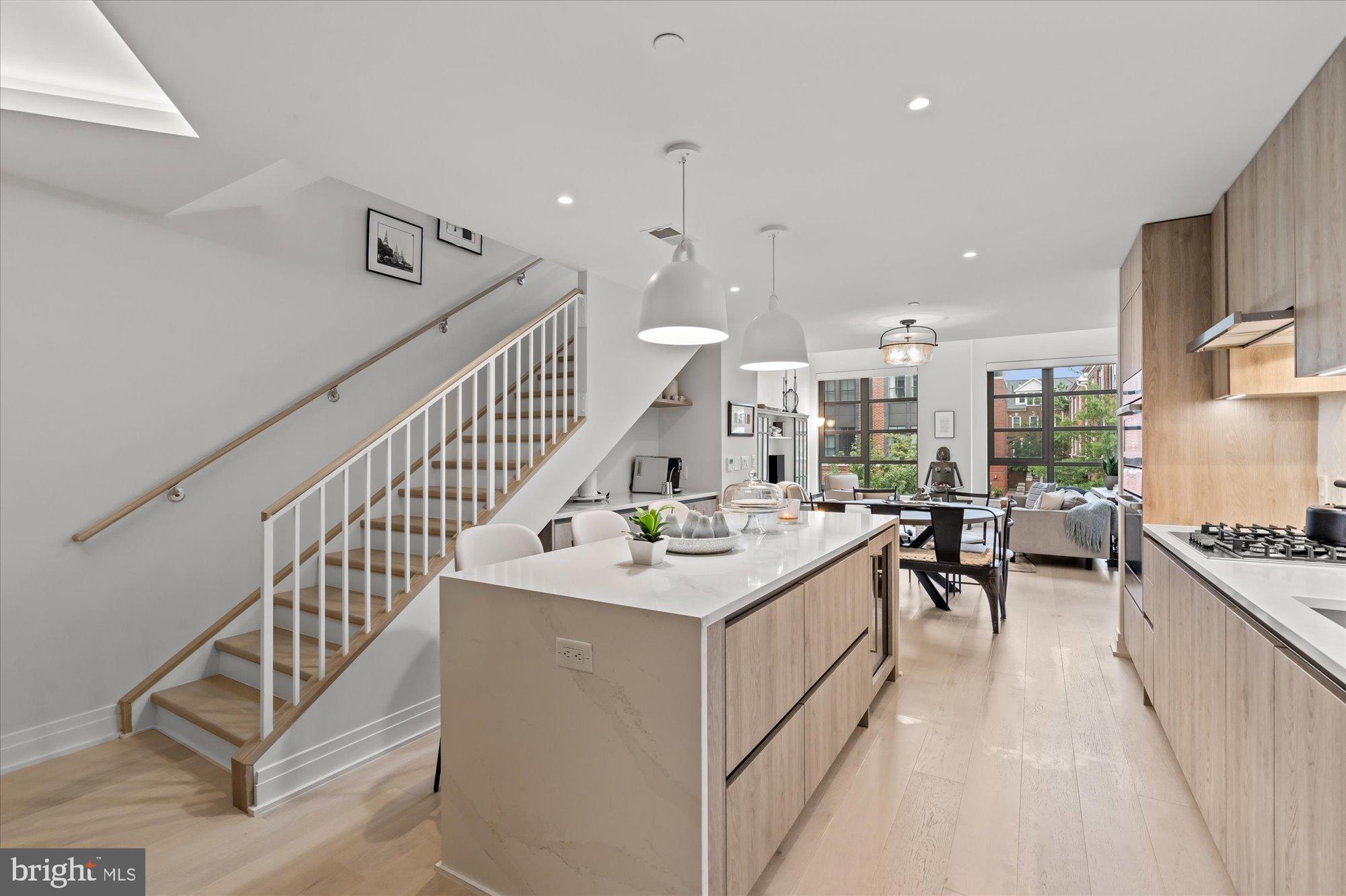 1201 North Royal Street, Unit 214 Alexandria, VA 22314 - Photo 4 of 71 a view of a kitchen with kitchen island a stove a sink a dining table and chairs