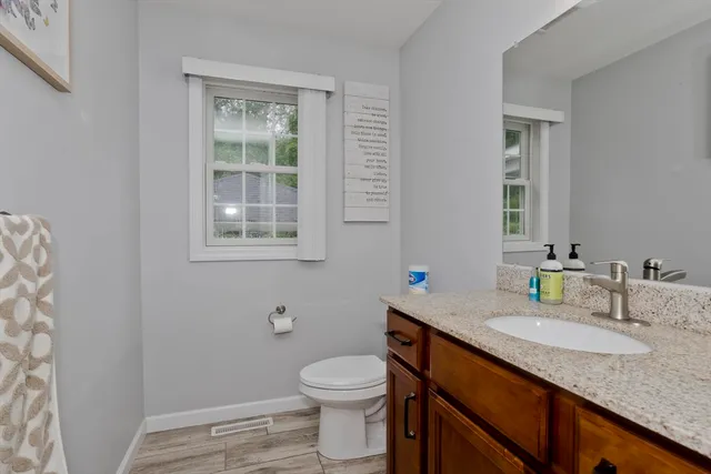 a bathroom with a granite countertop toilet sink and mirror