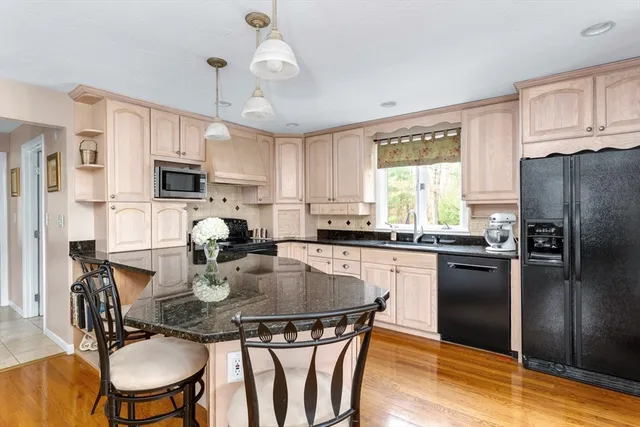 a kitchen with refrigerator a sink dining table and chairs