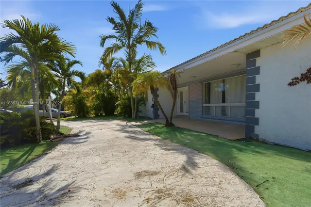 a backyard of a house with potted plants and palm trees