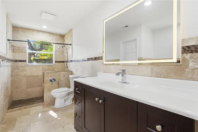 a bathroom with a sink a toilet a mirror and shower