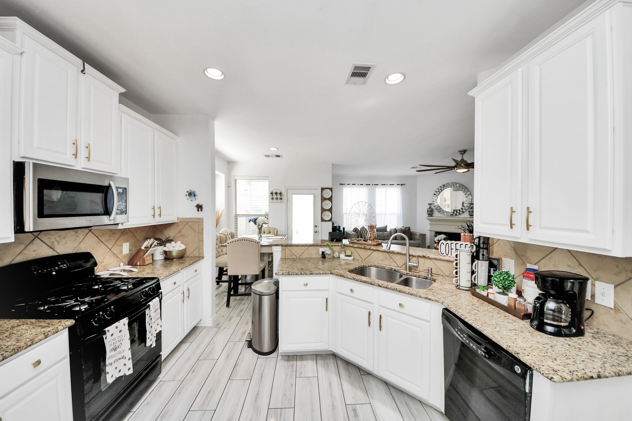 12119 Redbud Brook Trail Houston, TX 77089 - Photo 20 of 48 a kitchen with a sink dishwasher stove and white cabinets with wooden floor