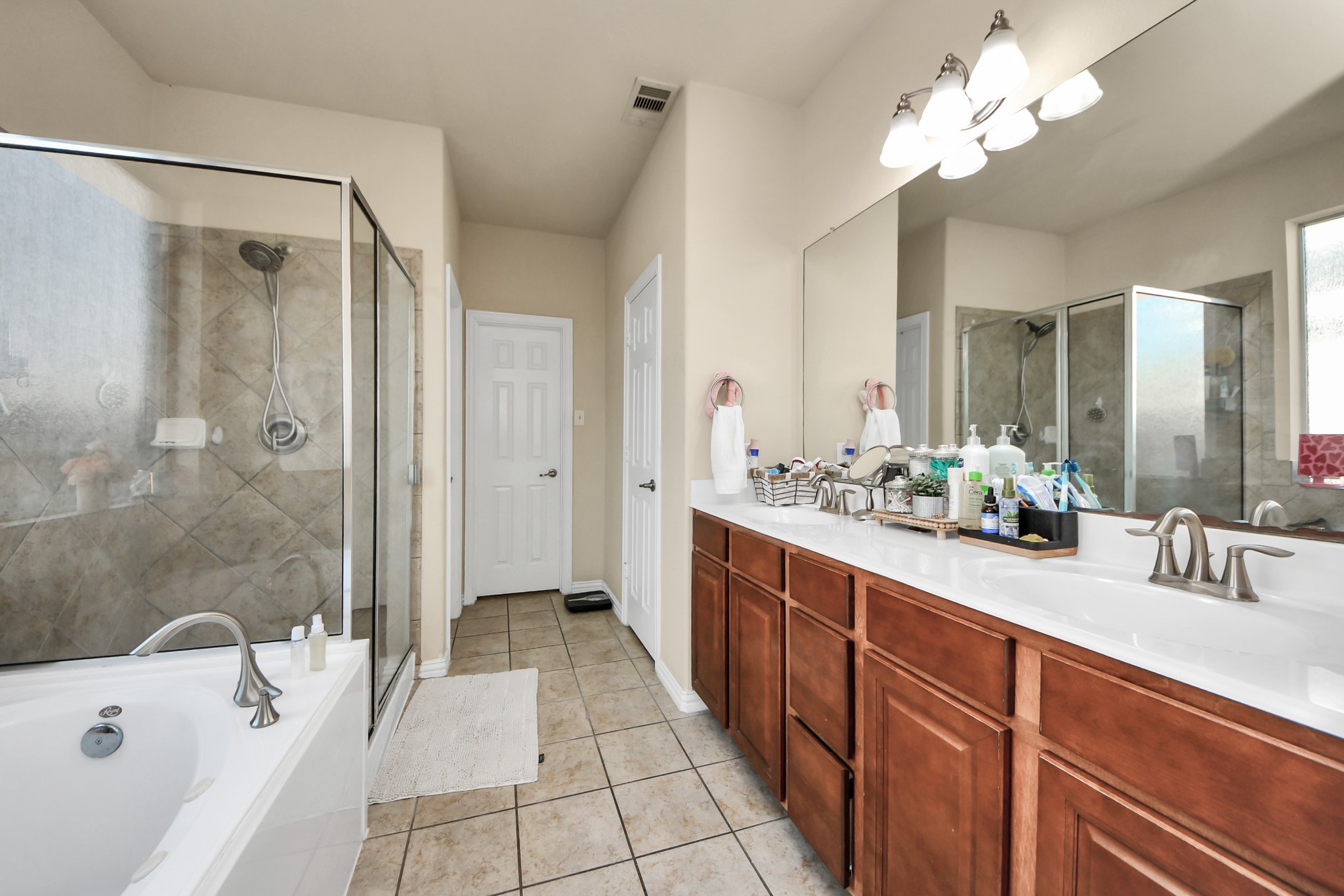 12119 Redbud Brook Trail Houston, TX 77089 - Photo 33 of 48 a bathroom with a double vanity sink a large mirror and a bathtub