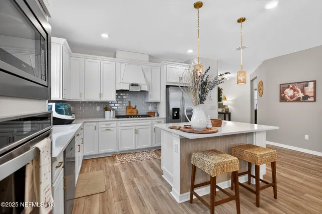 a kitchen with stainless steel appliances granite countertop a sink a stove a refrigerator and island with wooden floor