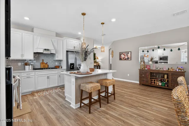 a kitchen with stainless steel appliances granite countertop a table chairs sink and cabinets