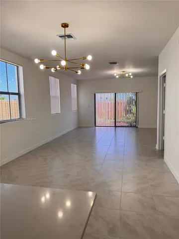 a view of an empty room with a chandelier fan and windows