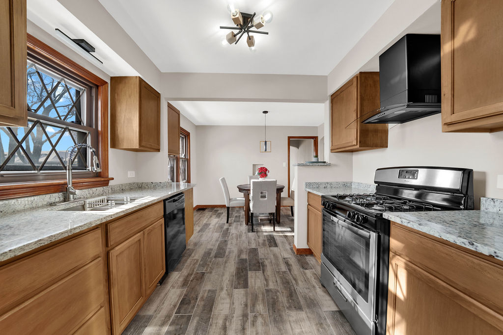 6559 South Kilpatrick Avenue Chicago, IL 60629 - Photo 7 of 26 a kitchen with stainless steel appliances granite countertop a stove top oven a sink dishwasher a dining table and chairs with wooden floor