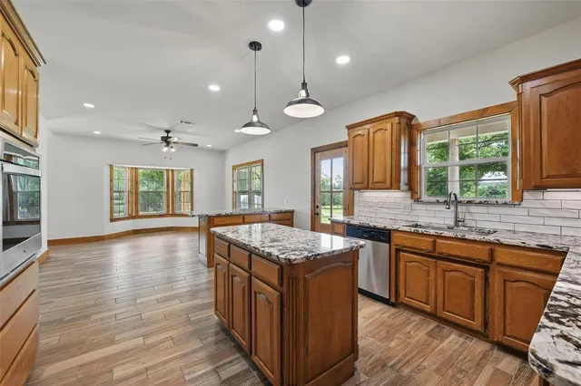 a kitchen with stainless steel appliances granite countertop wooden floors and sink