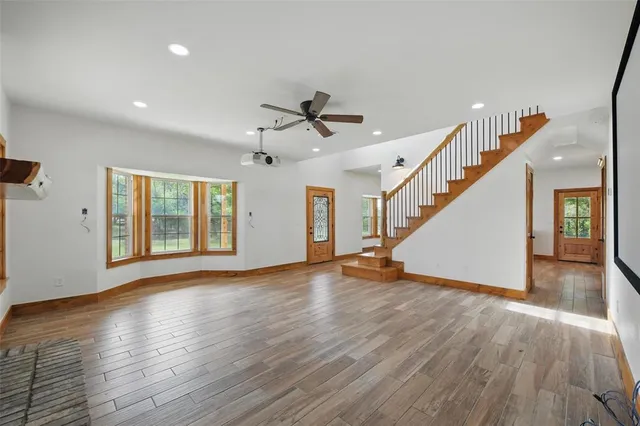 a view of an empty room with wooden floor and a ceiling fan