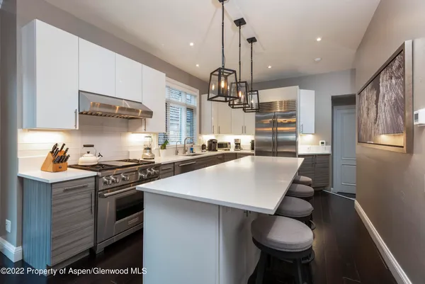 a kitchen with stainless steel appliances kitchen island a table chairs stove and cabinets