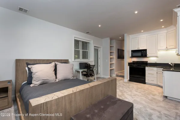 a large bedroom with a large bed and a view of kitchen
