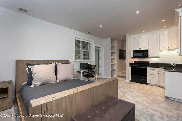 a large bedroom with a large bed and a view of kitchen