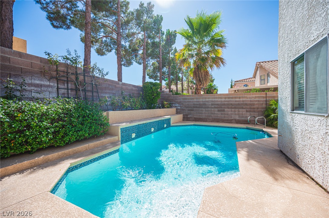 718 Rusty Spur Drive Henderson, NV 89014 - Photo 26 of 50 A tranquil inground pool with a tiled accent wall and lush landscaping provides a private backyard oasis.
