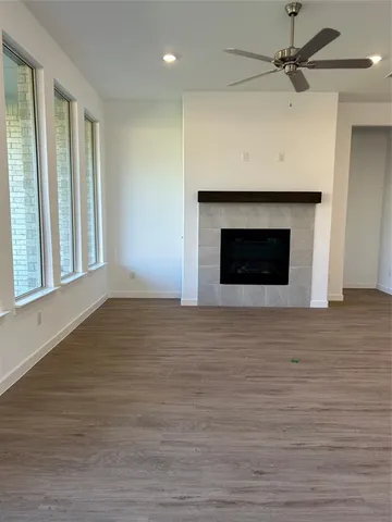 a view of empty room with wooden floor and a fireplace