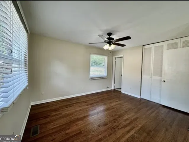 a view of an empty room with wooden floor and a window