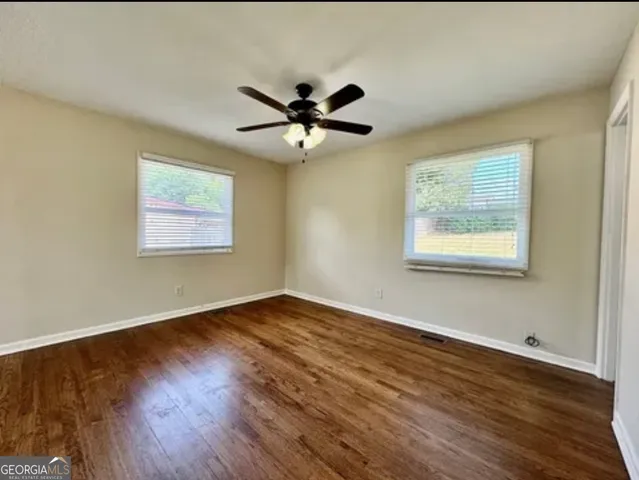 a view of an empty room with wooden floor and a window