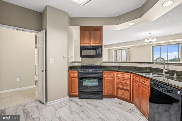 a kitchen with granite countertop a stove top oven a sink dishwasher and wooden cabinets with wooden floor