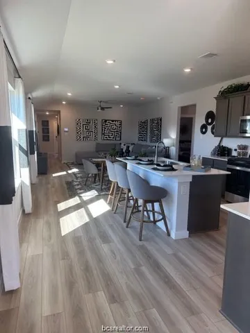 a kitchen with stainless steel appliances kitchen island granite countertop a table chairs sink and cabinets