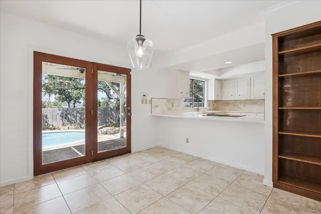 a view of an empty room with chandelier fan and fire place