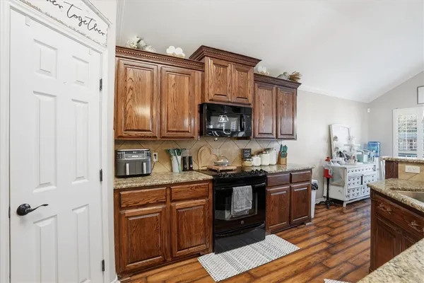 a kitchen with stainless steel appliances granite countertop a stove top oven a sink dishwasher and cabinets with wooden floor