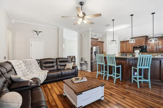 a living room with furniture kitchen view and a wooden floor