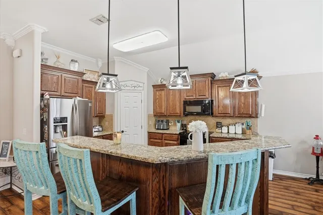 a kitchen with stainless steel appliances granite countertop a sink a refrigerator and chairs