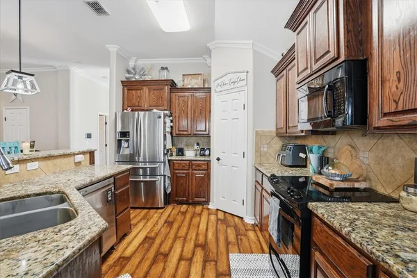 a kitchen with stainless steel appliances granite countertop a stove top oven a sink dishwasher a refrigerator and cabinets with wooden floor