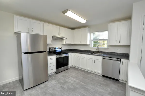 a kitchen with granite countertop white cabinets and refrigerator