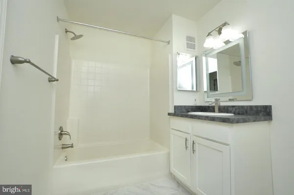 a bathroom with a granite countertop sink a mirror a shower and a bathtub
