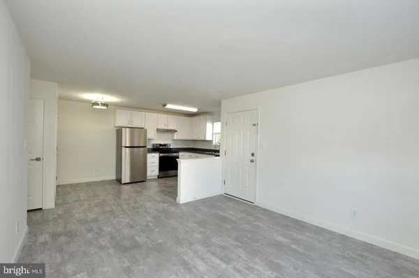 a view of kitchen refrigerator and white cabinets